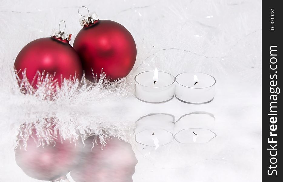 Candles and red Christmas ornaments surrounded by snowy tinsel and ice. Candles and red Christmas ornaments surrounded by snowy tinsel and ice