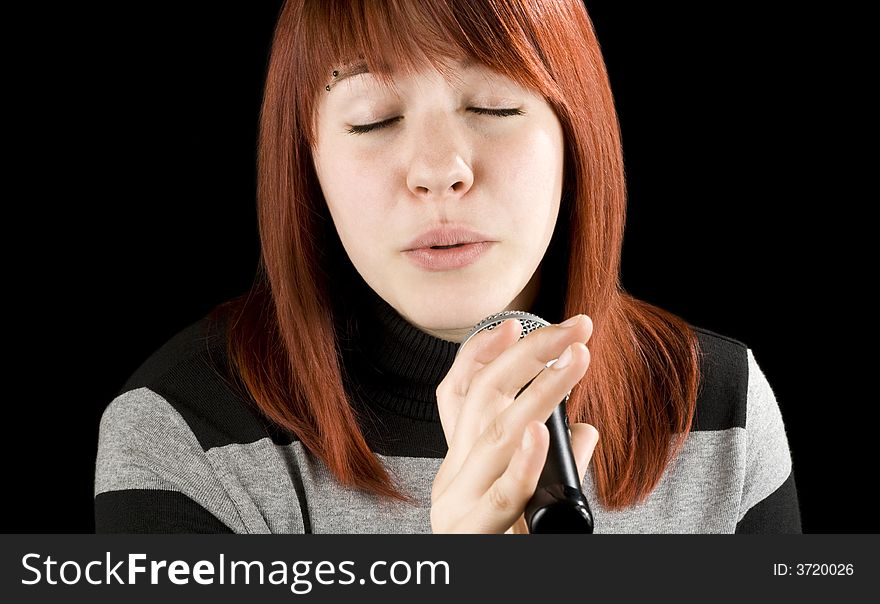 Redhead girl singing karaoke with a microphone. Sweet face.

Studio shot.