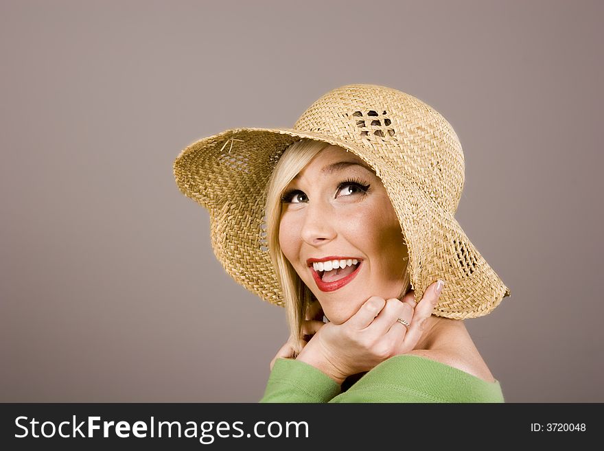A beautiful fashion model smiling in a straw hat. A beautiful fashion model smiling in a straw hat