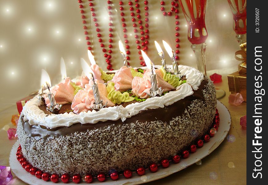 Celebratory table (cake and candles, two glasses with champagne, gift boxes)