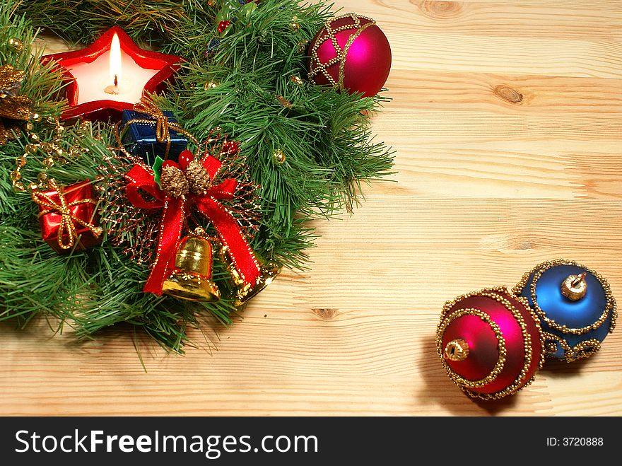 Green Xmas wreath with a candle and different decorations against wooden desk. Green Xmas wreath with a candle and different decorations against wooden desk