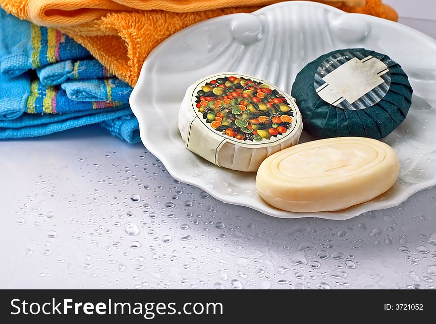 Three bath soaps with towels in the background and droplets. Three bath soaps with towels in the background and droplets