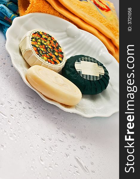 Three bath soaps with towels in the background and droplets. Three bath soaps with towels in the background and droplets