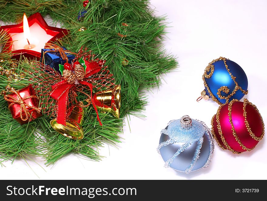 Isolated green Xmas wreath with a candle and different decorations against white background