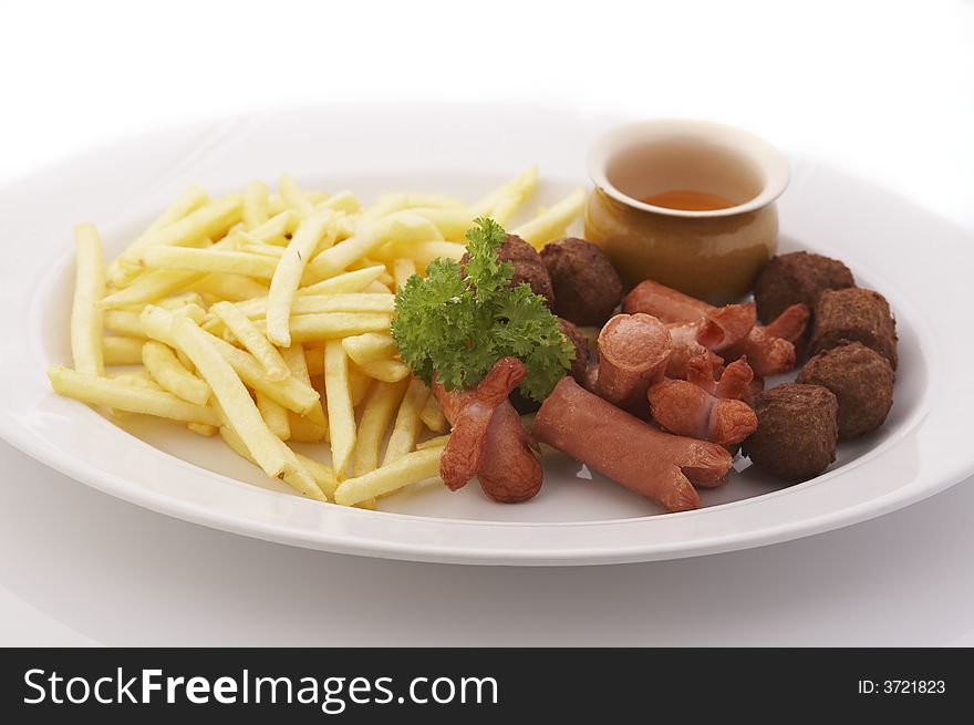 French fries, meatballs and sausages on the plate over a white background. French fries, meatballs and sausages on the plate over a white background