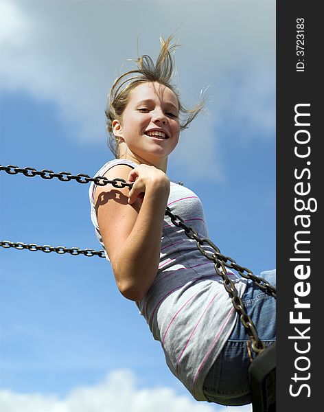 Smiling teenage girl aloft on a childs swing. Smiling teenage girl aloft on a childs swing