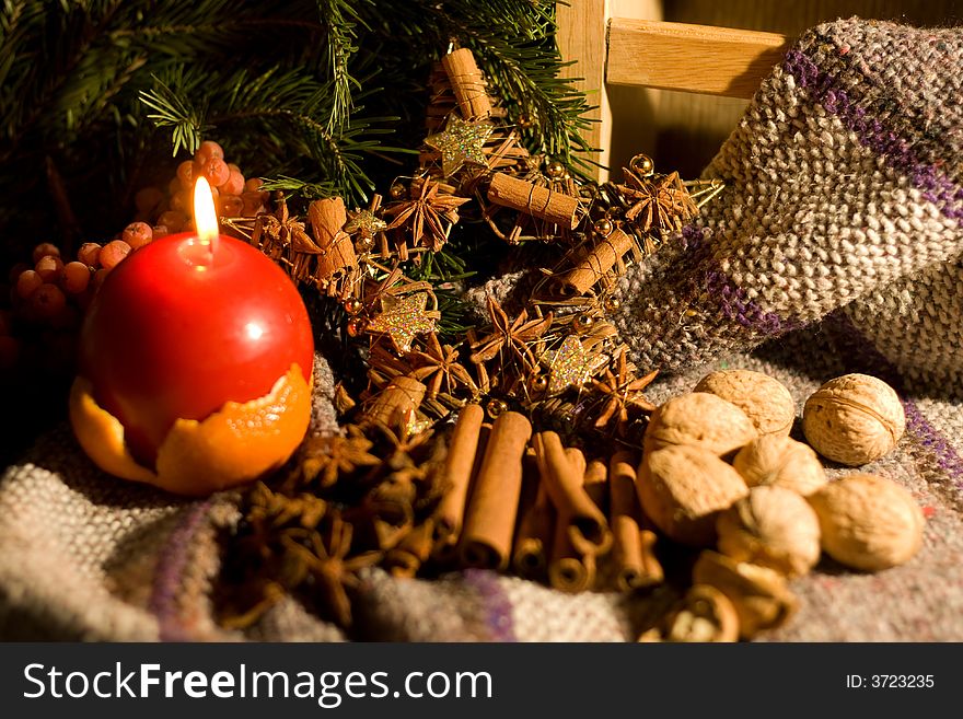 Christmas decoration - candle, nuts and spices on rough fabric. Christmas decoration - candle, nuts and spices on rough fabric