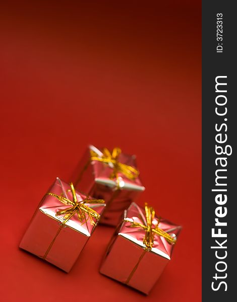 Little boxes with gifts on red background. Low DOF, copy space on top