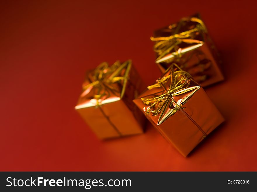 Little boxes with gifts on red background. Low DOF, copy space on left