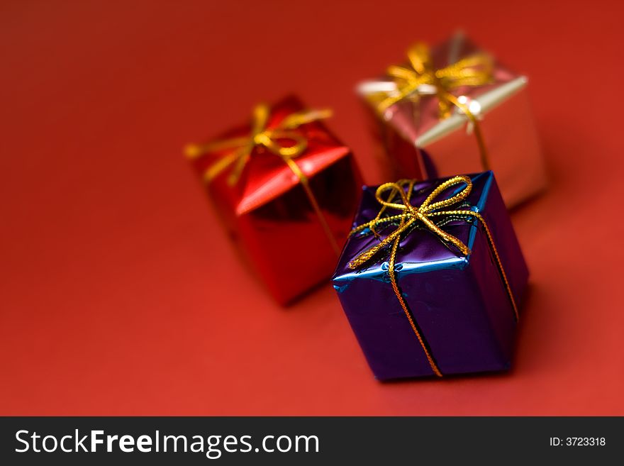 Little boxes with gifts on red background. Low DOF, copy space on left