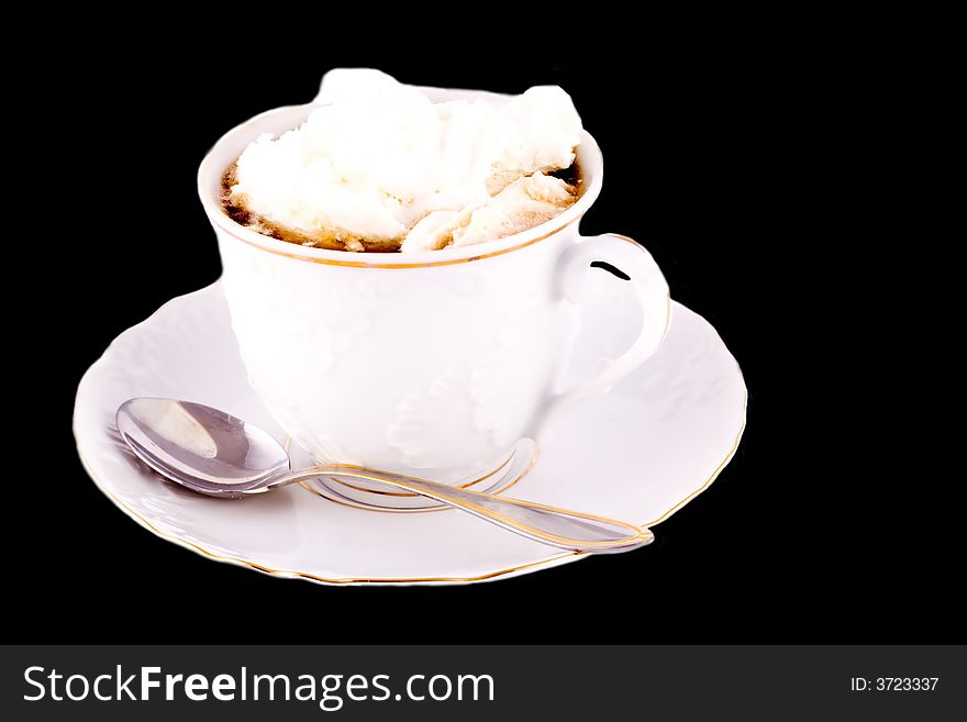 A cup of coffee topped with cream on black