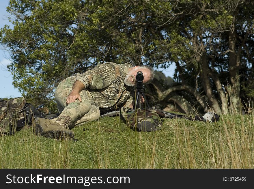 Hunter looking through spotting scope for game. Hunter looking through spotting scope for game