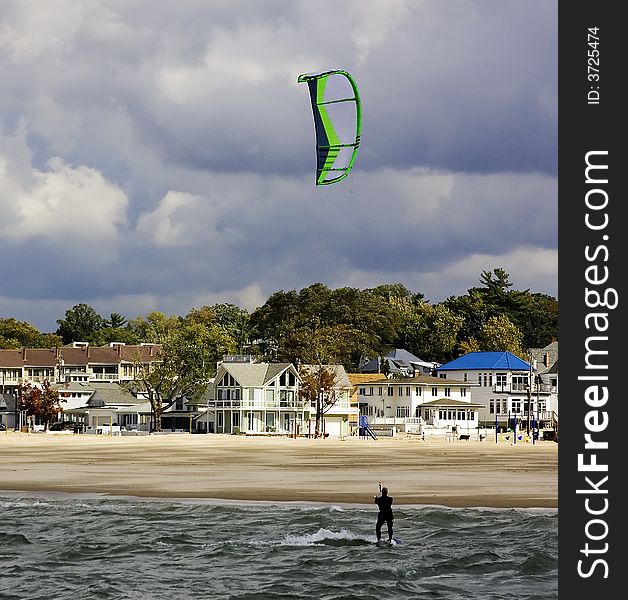 A wind surfer returns to the beach as storm clouds loom. A wind surfer returns to the beach as storm clouds loom