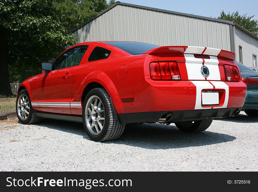 2007 Ford Mustang Shelby Cobra, GT 500, rear view. Red automobile with white racing stripes. 2007 Ford Mustang Shelby Cobra, GT 500, rear view. Red automobile with white racing stripes.
