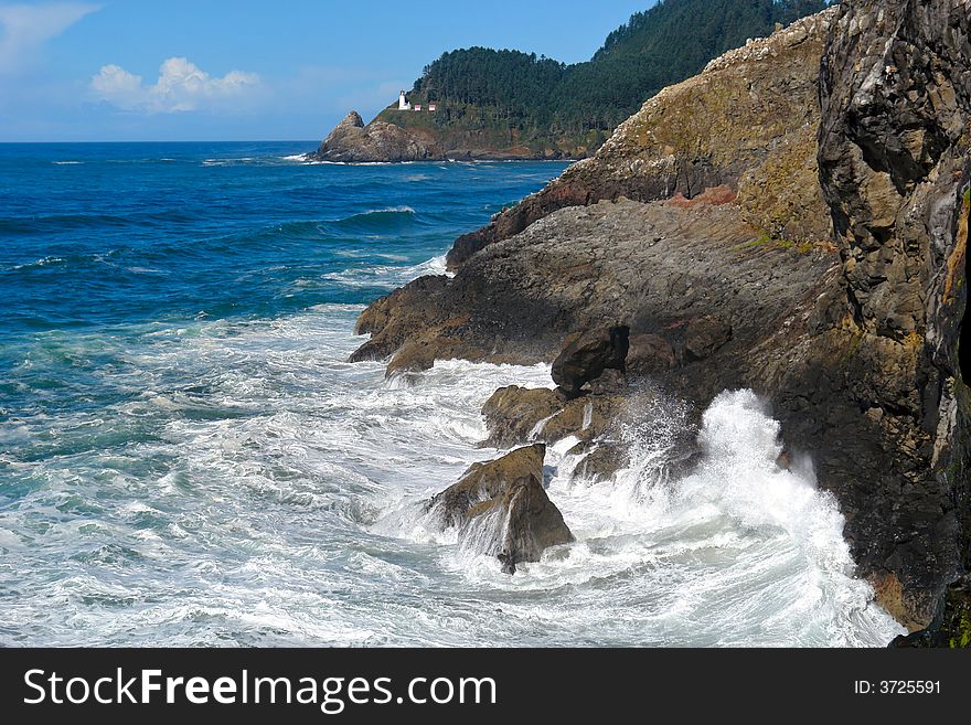 Beautiful dramatic scenic image of the waves crashing upon the rocky coast with light house in the background. Beautiful dramatic scenic image of the waves crashing upon the rocky coast with light house in the background