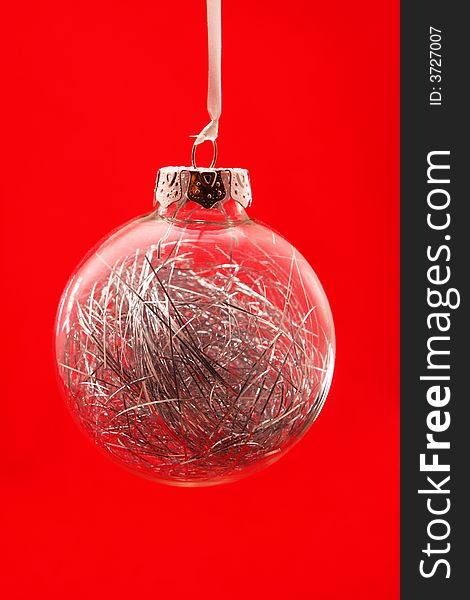 Clear christmas orb ornament, shot on red background, silver threads inside orb. Clear christmas orb ornament, shot on red background, silver threads inside orb