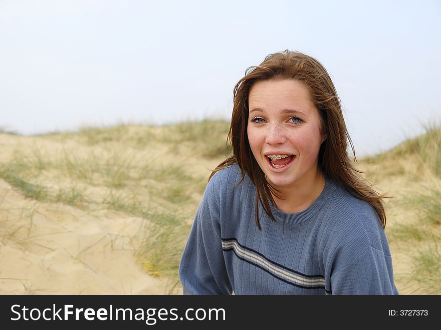 Laughing girl in sand dunes, looking at camera