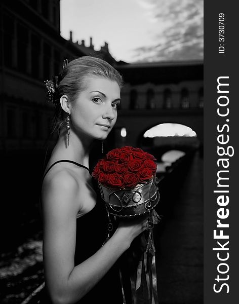 Black and white picture of a beautiful girl with roses  in old city