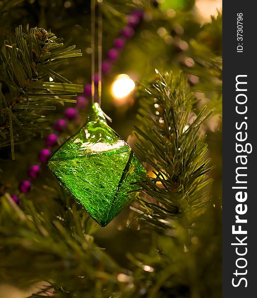 A double tetrahedral green ornament full of fractured textures withing its translucent body hanging on a Christmas tree