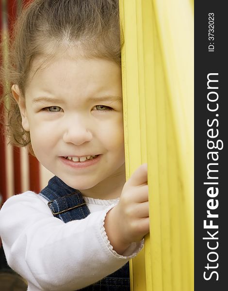 Little girl on play equipment smiles at the camera. Little girl on play equipment smiles at the camera