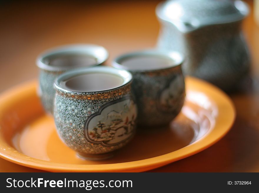 Teapot and three cups fillied with black tea. Selective focus.