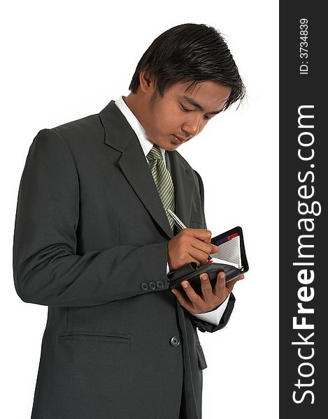 Businessman writing on his personal organizer over a white background