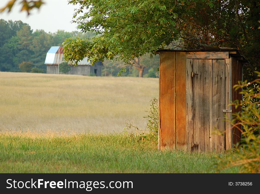 An old country outhouse near an open field