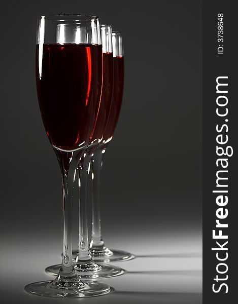 Three glasses with red wine on a dark background