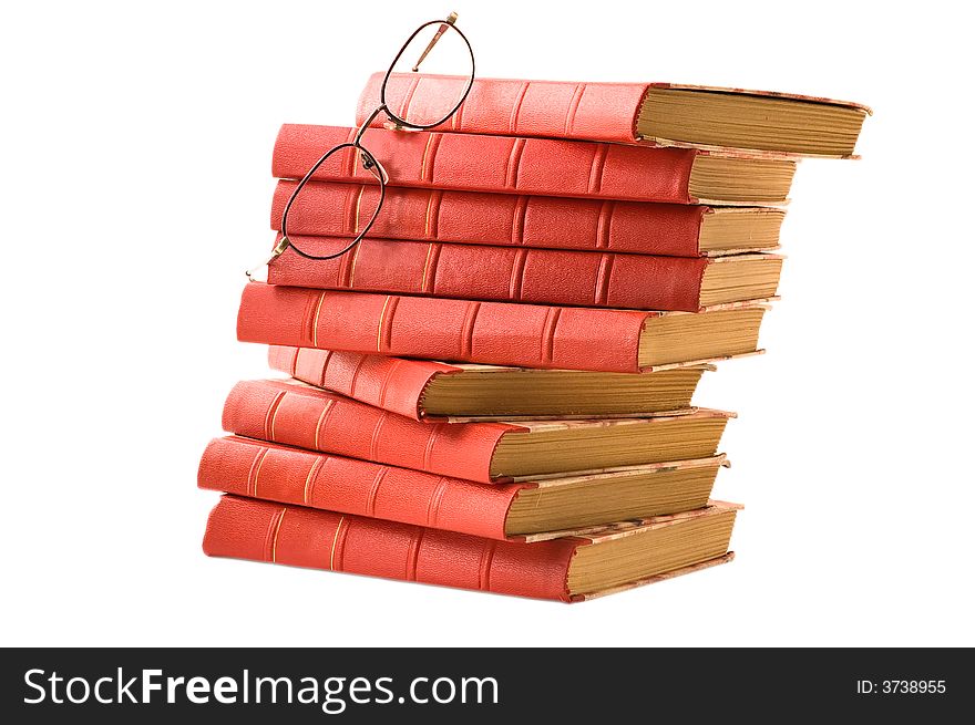 A pile of old red books and glasses on white background. A pile of old red books and glasses on white background
