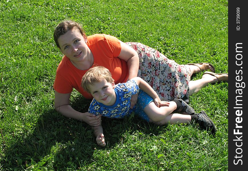Mother and her small son sitting on green grass. Mother and her small son sitting on green grass