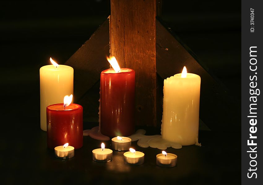 Candles set against a rough wood beam in the darkness. Candles set against a rough wood beam in the darkness