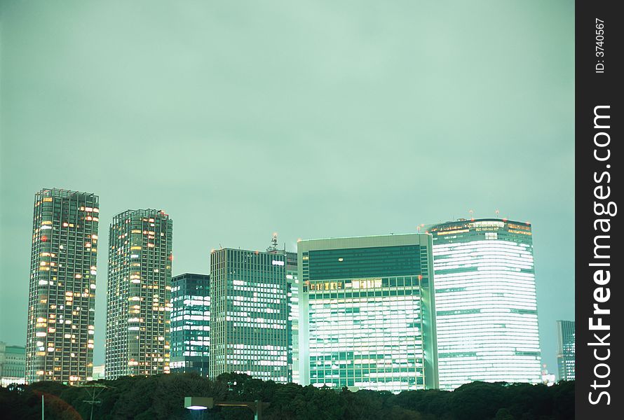 A nice view of a big city on night with green sky and some builds with a special lights