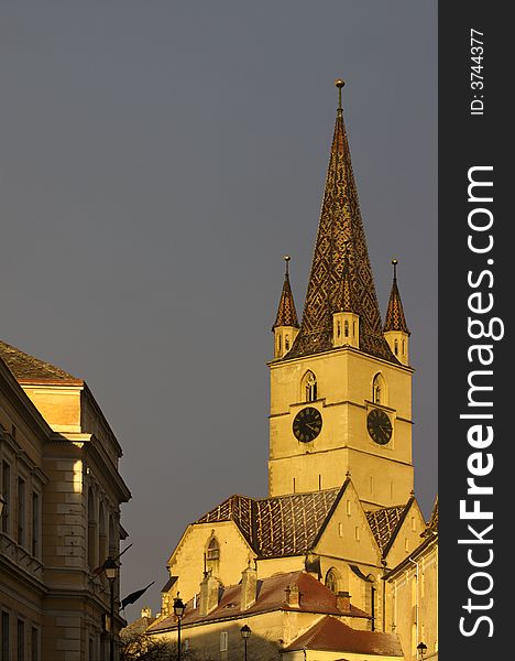 The Tower of the Evangelic Church in Sibiu, (European Capital of Culture 2007) with gray sky and clouds in the background, at sunset. The Tower of the Evangelic Church in Sibiu, (European Capital of Culture 2007) with gray sky and clouds in the background, at sunset