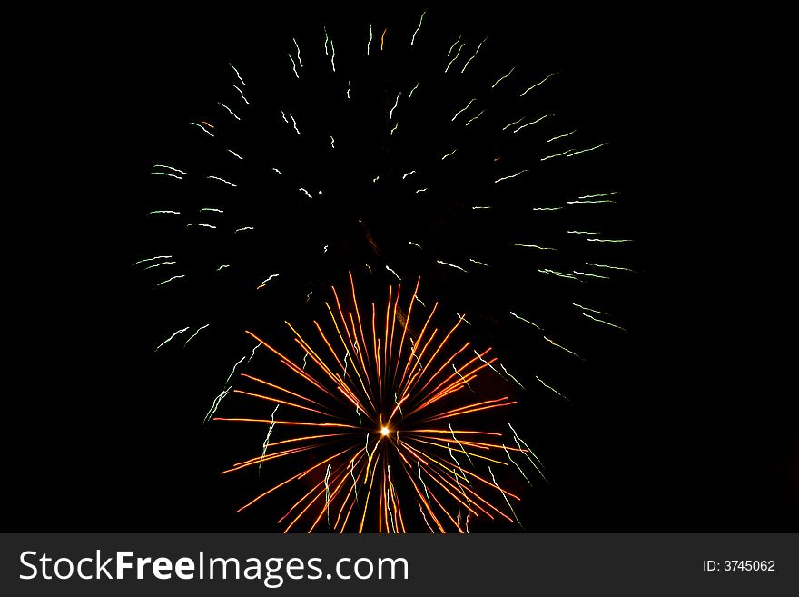 Red, white, green fireworks over dark sky