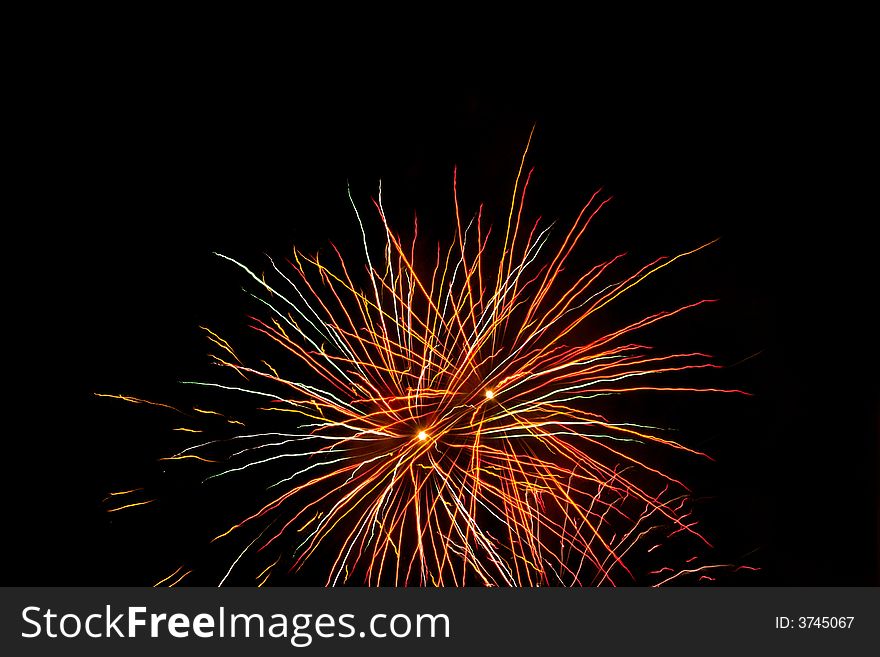 Red, white, green fireworks over dark sky