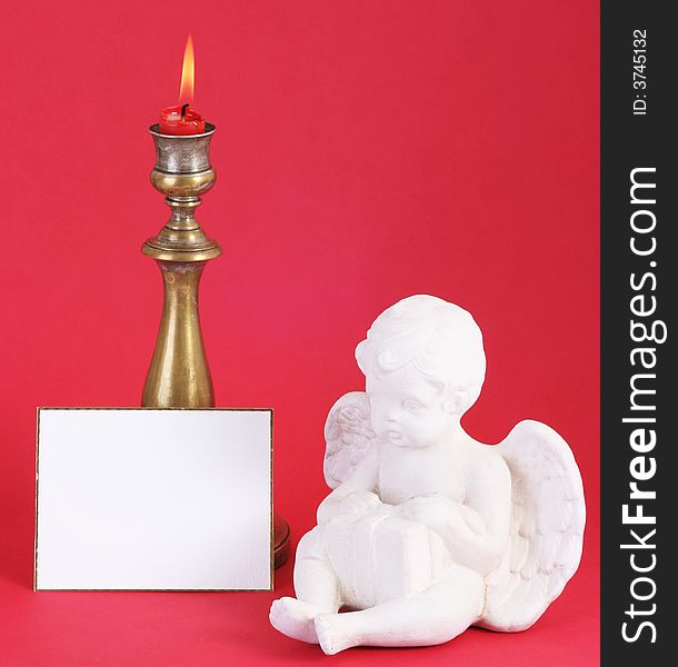 Christmas candle with flame.A white card in front.Red background. Christmas candle with flame.A white card in front.Red background.