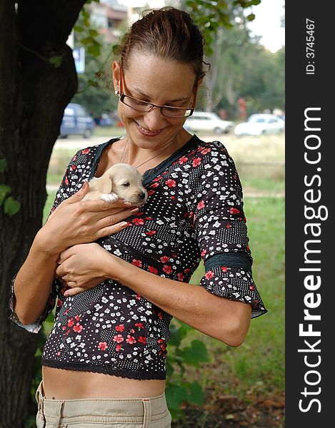 Teenage girl holding a puppy outdoors with green grass background. Teenage girl holding a puppy outdoors with green grass background