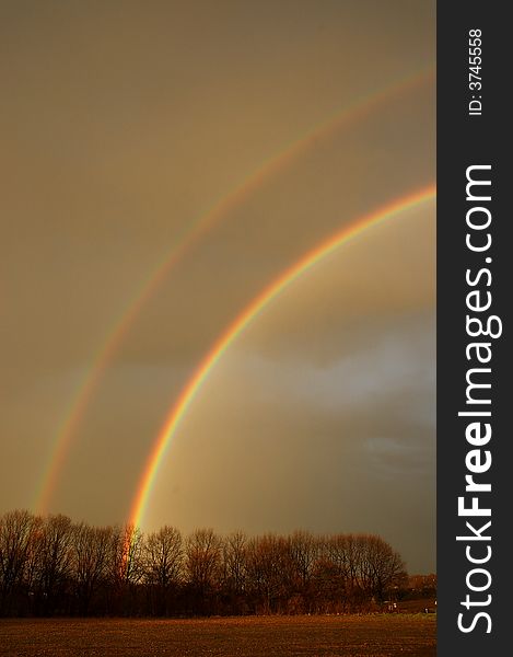 A doube rainbow in a field with trees. A doube rainbow in a field with trees