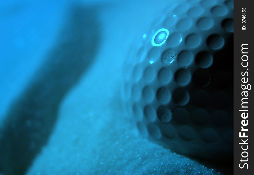 Close-up of golf ball in sand with blue ighting effect. Close-up of golf ball in sand with blue ighting effect