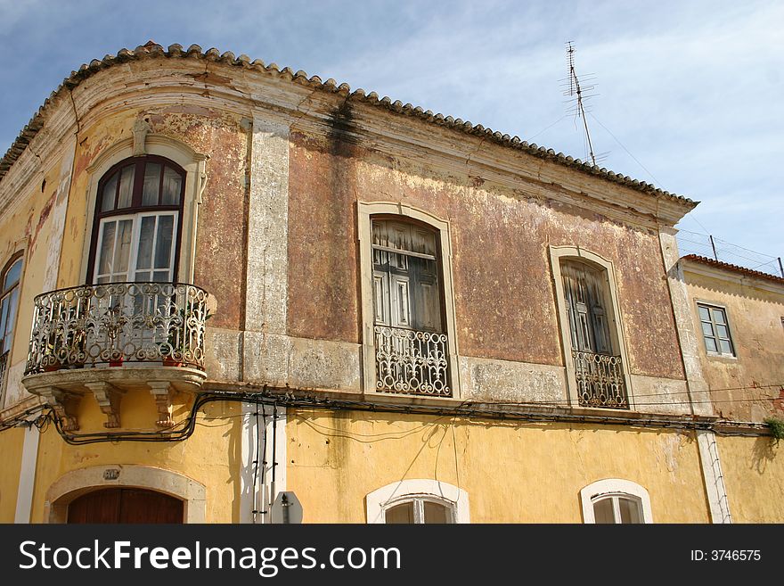 Rustic apartment building in Portimao, Portugal showing sun damaged stucco and rusted wrought iron balconies