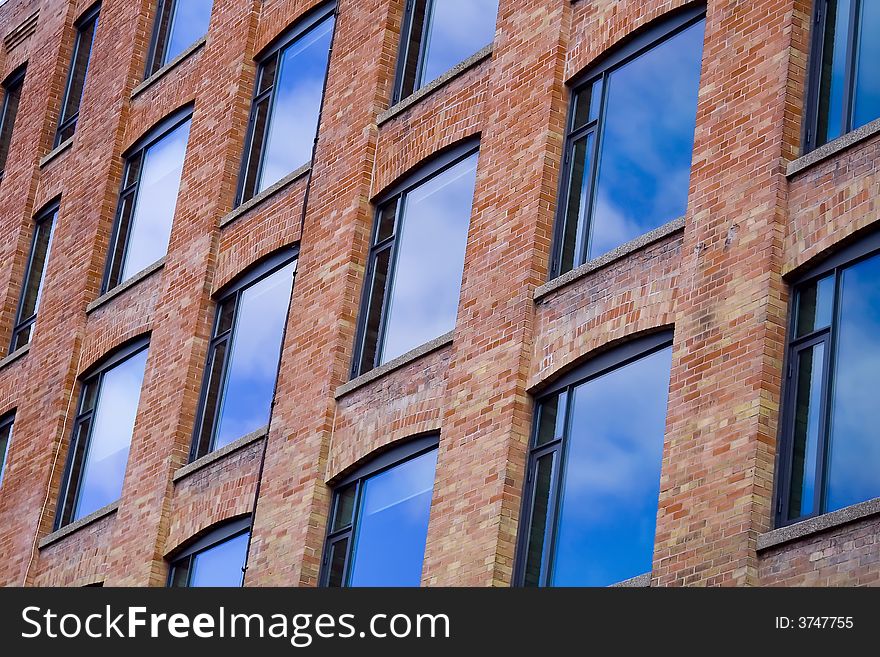 Windows on a brick building clouds & reflection