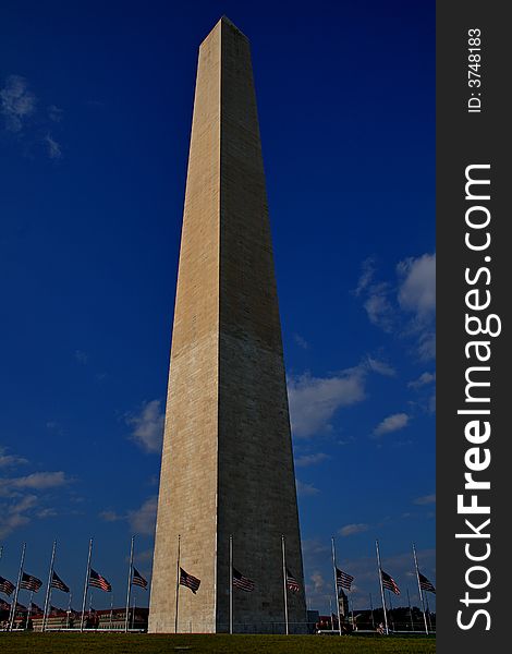 Washington Monument under a perfect blue sky, with the US flag being flown at half-staff