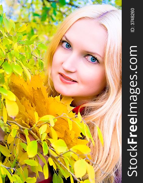 Autumn girl holding yellow leaves over blur background