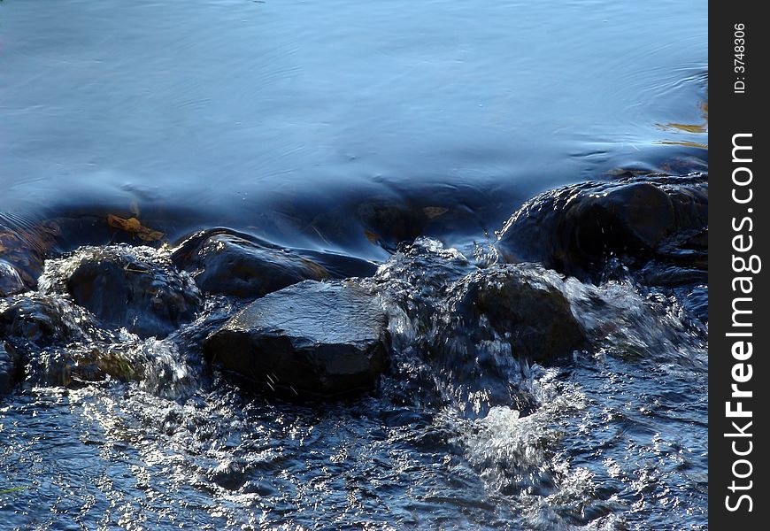 Blue water in a creek flowing over rocks. Blue water in a creek flowing over rocks.