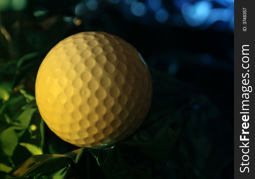 Close up of golf ball on crumpled foil with yellow lighting effect. Close up of golf ball on crumpled foil with yellow lighting effect