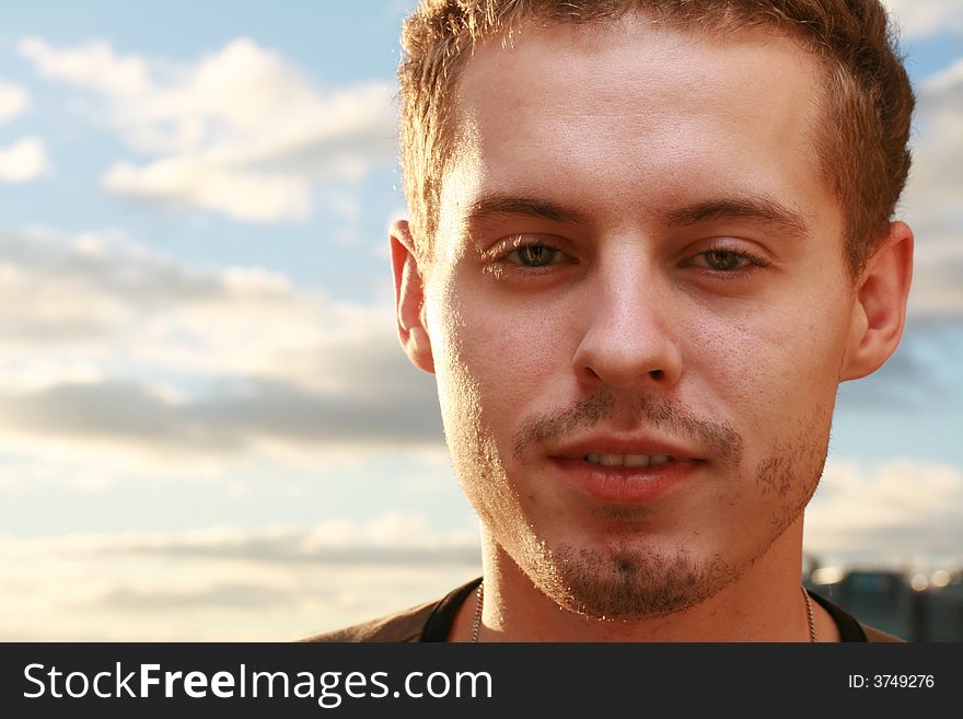 Young man against blue cloudy sky