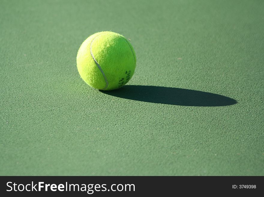 Single tennis ball on hard court with shadow. Single tennis ball on hard court with shadow