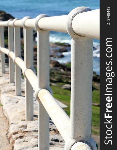 Looking along a curved white handrail by the ocean. Looking along a curved white handrail by the ocean