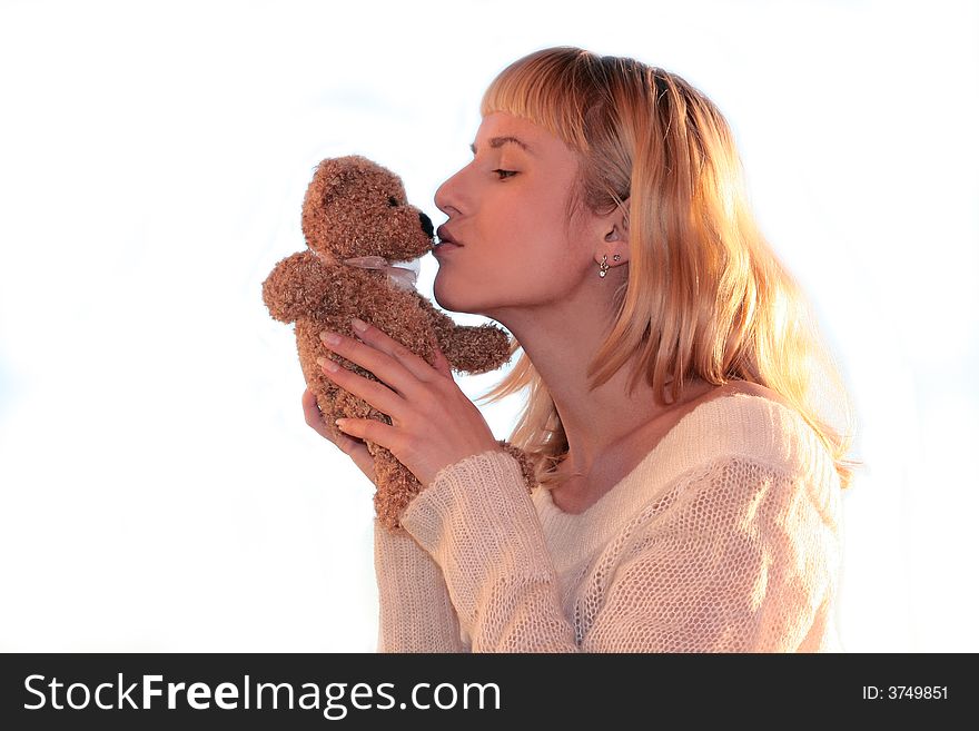 Young blond woman is kissing teddy bear
