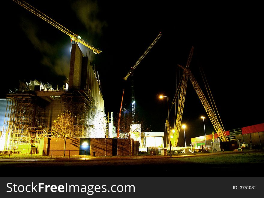 Buildingsite with cranes at night. Lights are kept on for workers at night.